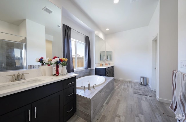 15920 Waterford St, Bakersfield, CA 93314 - bathroom with two vanities, a bath, a stall shower, wood finished floors, and recessed lighting