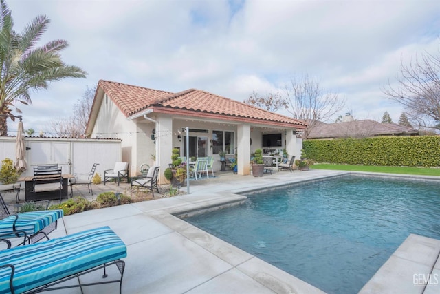 rear view of property with a fenced in pool and a patio area