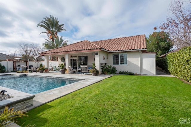 rear view of house featuring a fenced in pool, a patio area, and a lawn