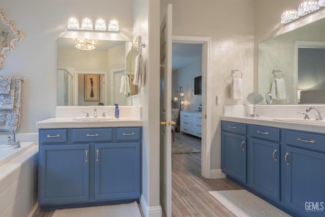 bathroom with vanity, a relaxing tiled tub, and wood-type flooring