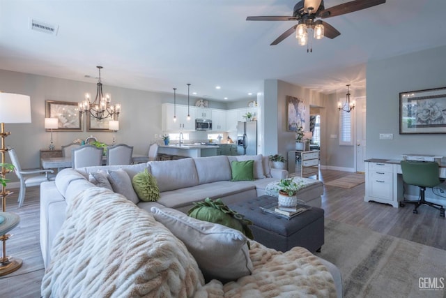 living room featuring hardwood / wood-style flooring, ceiling fan with notable chandelier, and sink