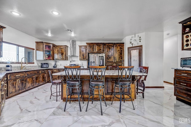 28124 Mustang Ave, Taft, CA 93268 - kitchen featuring wall chimney range hood, a sink, stainless steel fridge with ice dispenser, light marble finish floors, and a kitchen bar