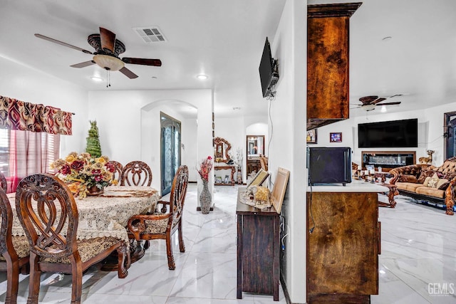 28124 Mustang Ave, Taft, CA 93268 - dining room with ceiling fan, arched walkways, light marble finish flooring, and a glass covered fireplace