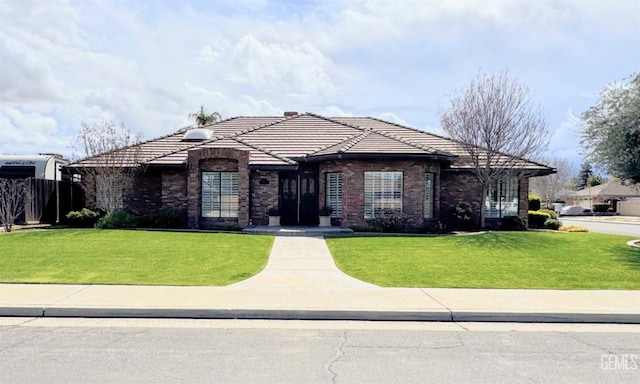 view of front of property with a front lawn, a tile roof, and brick siding