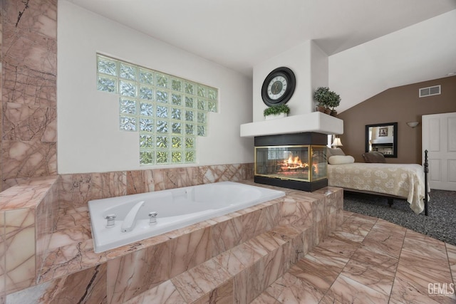 bathroom featuring lofted ceiling, a garden tub, a multi sided fireplace, visible vents, and ensuite bath