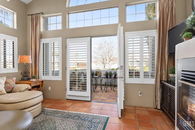 doorway featuring a towering ceiling, tile patterned flooring, and a wealth of natural light