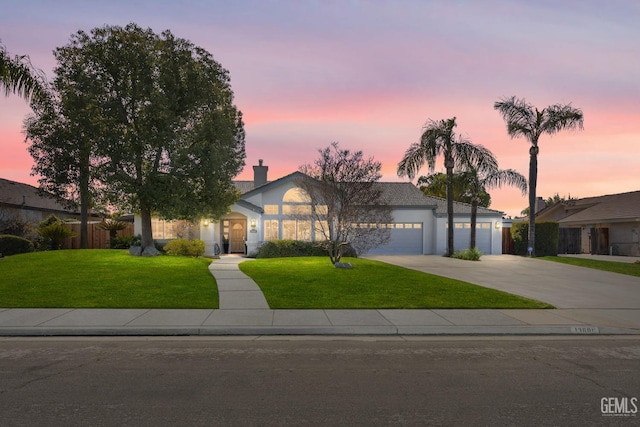 view of front of home featuring driveway, a lawn, an attached garage, and stucco siding