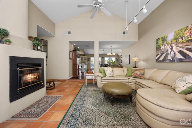 tiled living area featuring high vaulted ceiling, a glass covered fireplace, visible vents, and ceiling fan with notable chandelier