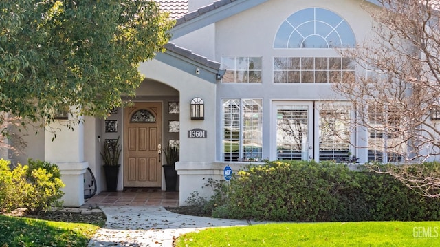 view of exterior entry featuring a tiled roof and stucco siding