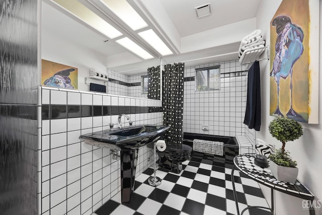 full bathroom featuring visible vents, a tile shower, tile walls, and tile patterned floors