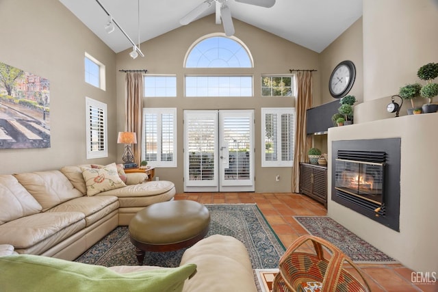 tiled living area with high vaulted ceiling, french doors, and a glass covered fireplace