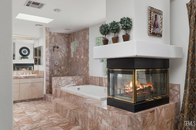 bathroom with a multi sided fireplace, vanity, visible vents, a bath, and walk in shower