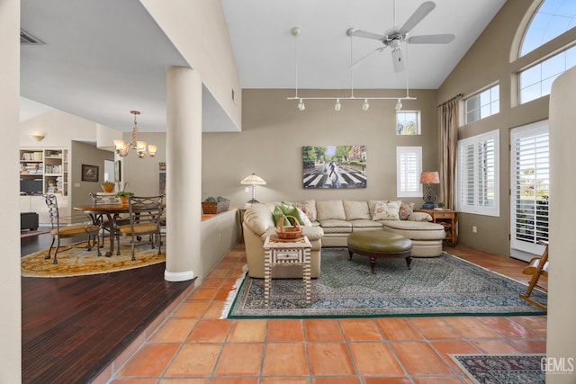 living area with visible vents, high vaulted ceiling, tile patterned flooring, and ceiling fan with notable chandelier