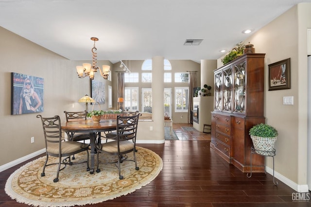 dining room with a notable chandelier, dark wood-type flooring, visible vents, and baseboards