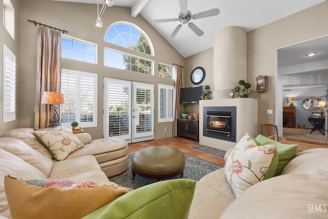 living area with a ceiling fan, a glass covered fireplace, tile patterned flooring, high vaulted ceiling, and beam ceiling