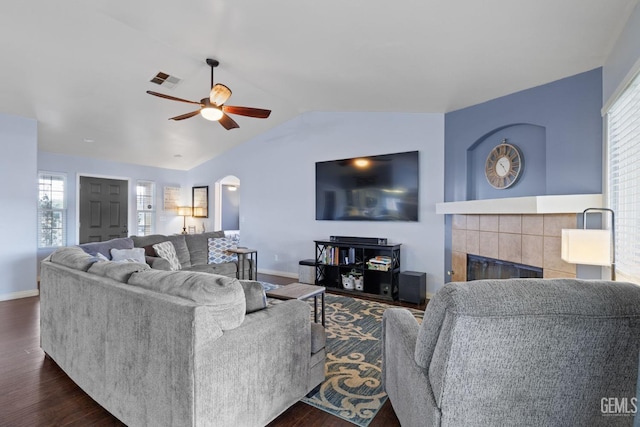 living area featuring visible vents, arched walkways, lofted ceiling, dark wood-type flooring, and a fireplace