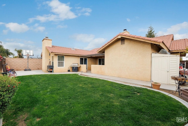 back of house with a patio, a chimney, stucco siding, a lawn, and fence