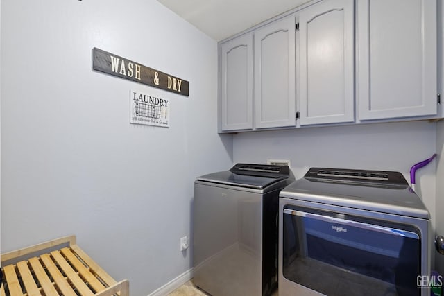 washroom with cabinet space, baseboards, and separate washer and dryer