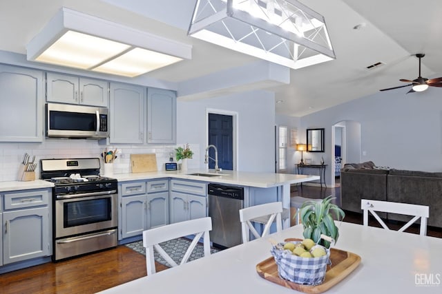 kitchen featuring arched walkways, stainless steel appliances, visible vents, a sink, and a peninsula