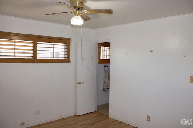 empty room featuring a ceiling fan, light wood-type flooring, crown molding, and baseboards