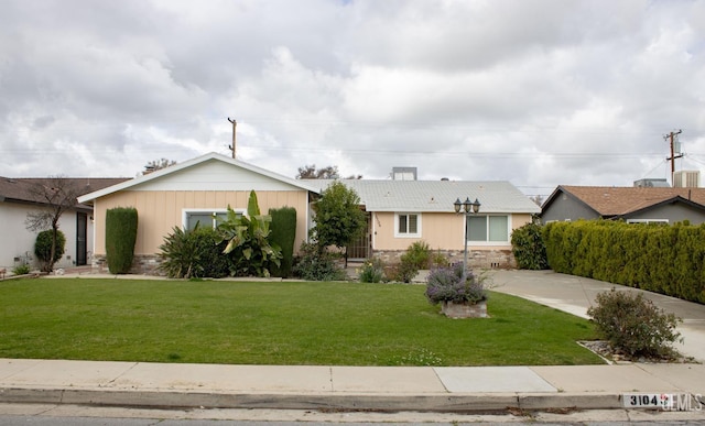 ranch-style home featuring stone siding and a front lawn