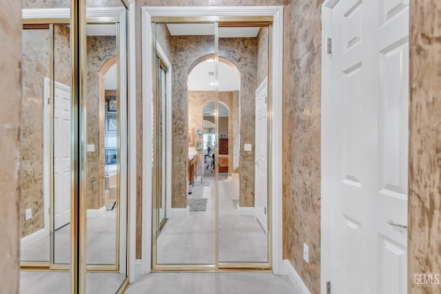 corridor with arched walkways and wallpapered walls