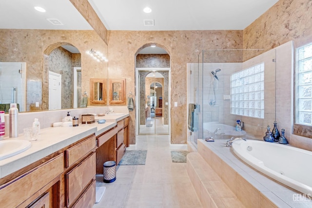 bathroom with a garden tub, double vanity, visible vents, a stall shower, and a sink