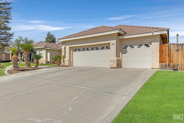 view of front of home with a garage, fence, a tile roof, concrete driveway, and stucco siding