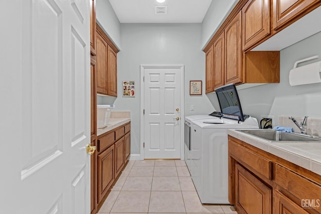 laundry area with light tile patterned floors, cabinet space, visible vents, a sink, and separate washer and dryer