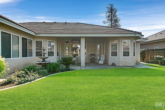 back of house featuring a yard, a patio area, fence, and stucco siding