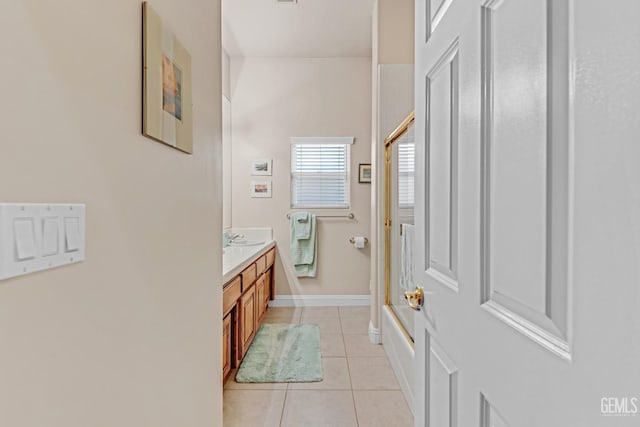 full bath with a shower with shower door, vanity, baseboards, and tile patterned floors