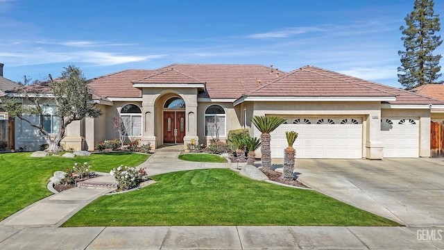 mediterranean / spanish-style house with an attached garage, driveway, a front lawn, and stucco siding