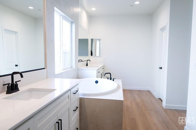 bathroom with vanity, wood-type flooring, and a tub to relax in