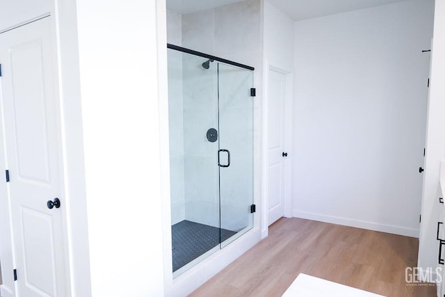 bathroom with a shower with door and wood-type flooring