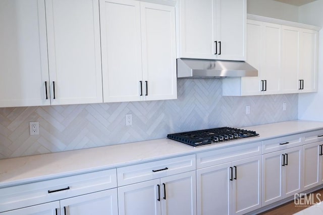 kitchen featuring white cabinetry, backsplash, light stone countertops, exhaust hood, and stainless steel gas stovetop