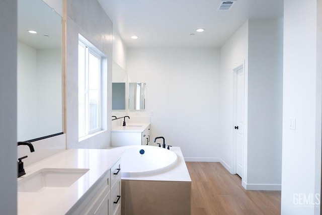 bathroom featuring vanity, a bath, and wood-type flooring