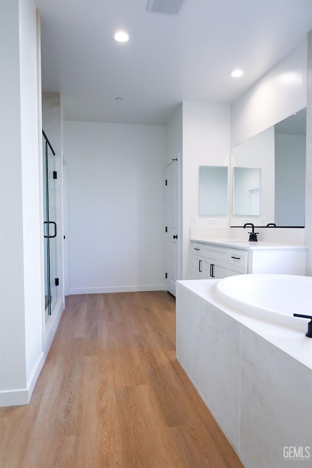 bathroom featuring independent shower and bath, wood-type flooring, and vanity