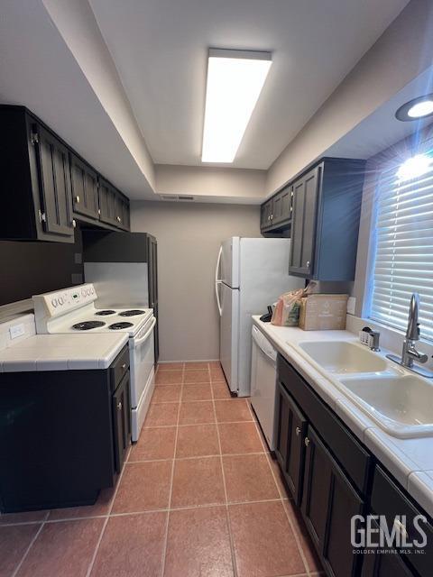 kitchen with sink, light tile patterned floors, and white appliances