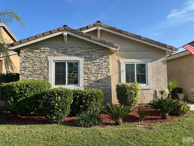 2114 Via Lazio Ave, Delano, CA 93215 - view of side of home with stone siding, a yard, a tiled roof, and stucco siding