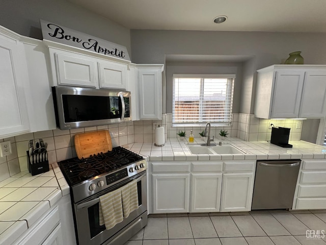 2114 Via Lazio Ave, Delano, CA 93215 - kitchen with stainless steel appliances, a sink, tile countertops, white cabinetry, and backsplash
