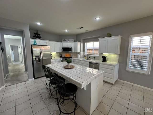 2114 Via Lazio Ave, Delano, CA 93215 - kitchen with stainless steel appliances, tile counters, a sink, light tile patterned flooring, and recessed lighting