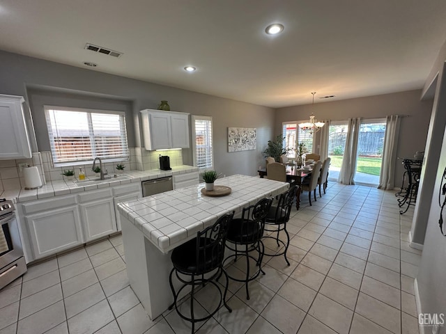 2114 Via Lazio Ave, Delano, CA 93215 - kitchen featuring a sink, tile counters, light tile patterned flooring, white cabinets, and recessed lighting