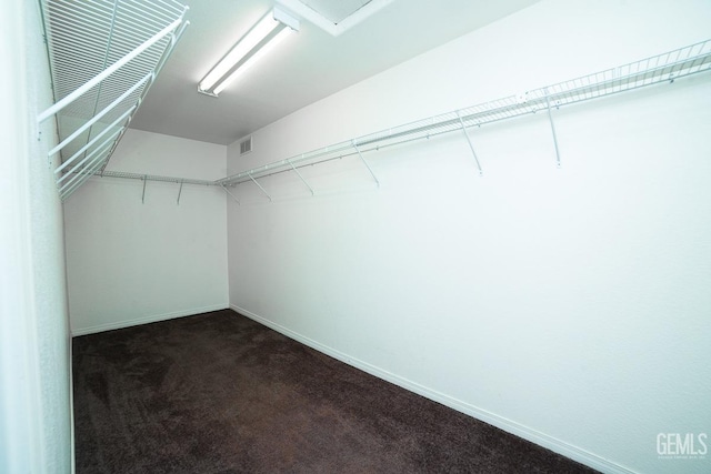 spacious closet featuring dark colored carpet