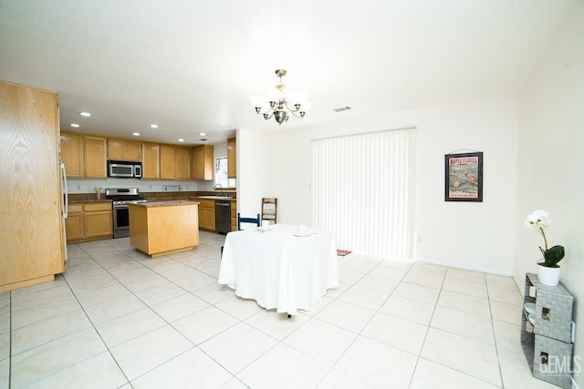 kitchen featuring stainless steel appliances, light tile patterned floors, a notable chandelier, a center island, and hanging light fixtures