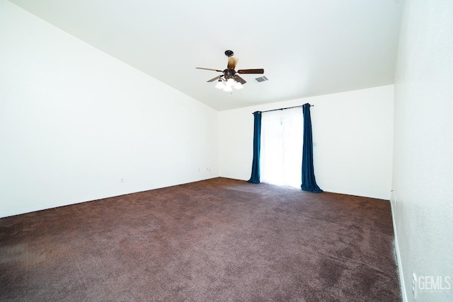 empty room featuring ceiling fan, dark carpet, and vaulted ceiling