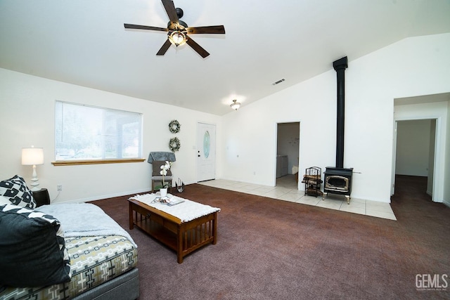 carpeted living room featuring ceiling fan, a wood stove, and vaulted ceiling