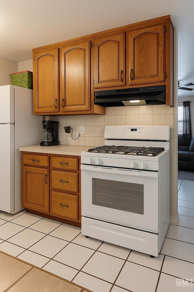 701 Burnett Dr, Bakersfield, CA 93307 - kitchen featuring white appliances, under cabinet range hood, light countertops, brown cabinetry, and tasteful backsplash
