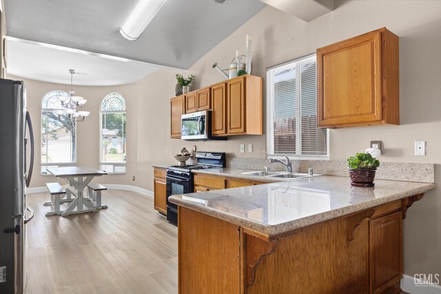 231 Sunny Meadow Dr, Bakersfield, CA 93308 - kitchen with appliances with stainless steel finishes, a sink, a peninsula, light wood finished floors, and a chandelier