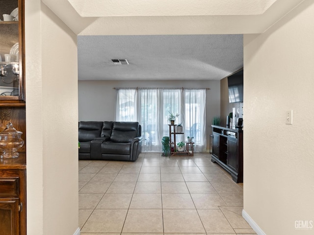 unfurnished living room with a textured ceiling and light tile patterned floors