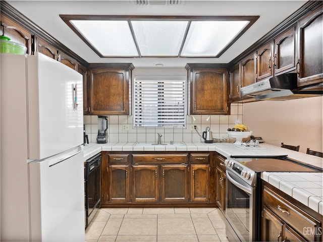 kitchen featuring white refrigerator, tile counters, electric range, and tasteful backsplash